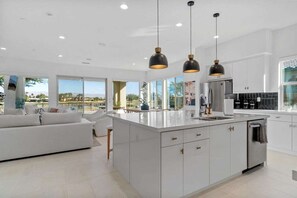 A modern kitchen with a central island, white cabinetry, and pendant lighting.