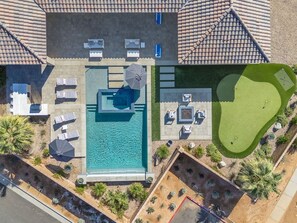 Vue aérienne d’une propriété dotée d’une piscine, de chaises longues et d’un terrain de golf.