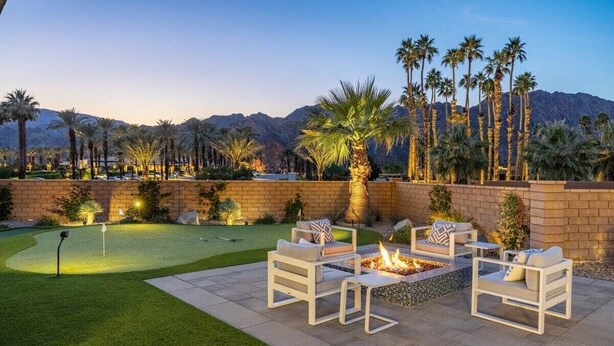 An outdoor patio with a fire pit and seating, a putting green, and palm trees. - Poolside Paradise | Fire Pit & Golf Next Door (La Quinta)