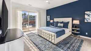 A bedroom with a large bed, a ceiling fan, and a view through a glass door. - Poolside Paradise | Fire Pit & Golf Next Door (La Quinta)
