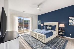 A bedroom with a large bed, a ceiling fan, and a view through a glass door. - Poolside Paradise | Fire Pit & Golf Next Door (La Quinta)