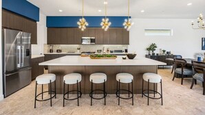 A modern kitchen with a central island, bar stools, and pendant lighting. - Poolside Paradise | Fire Pit & Golf Next Door (La Quinta)
