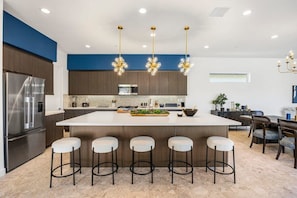 A modern kitchen with a central island, bar stools, and pendant lighting. - Poolside Paradise | Fire Pit & Golf Next Door (La Quinta)
