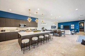 A modern kitchen with a central island, bar stools, and pendant lighting.