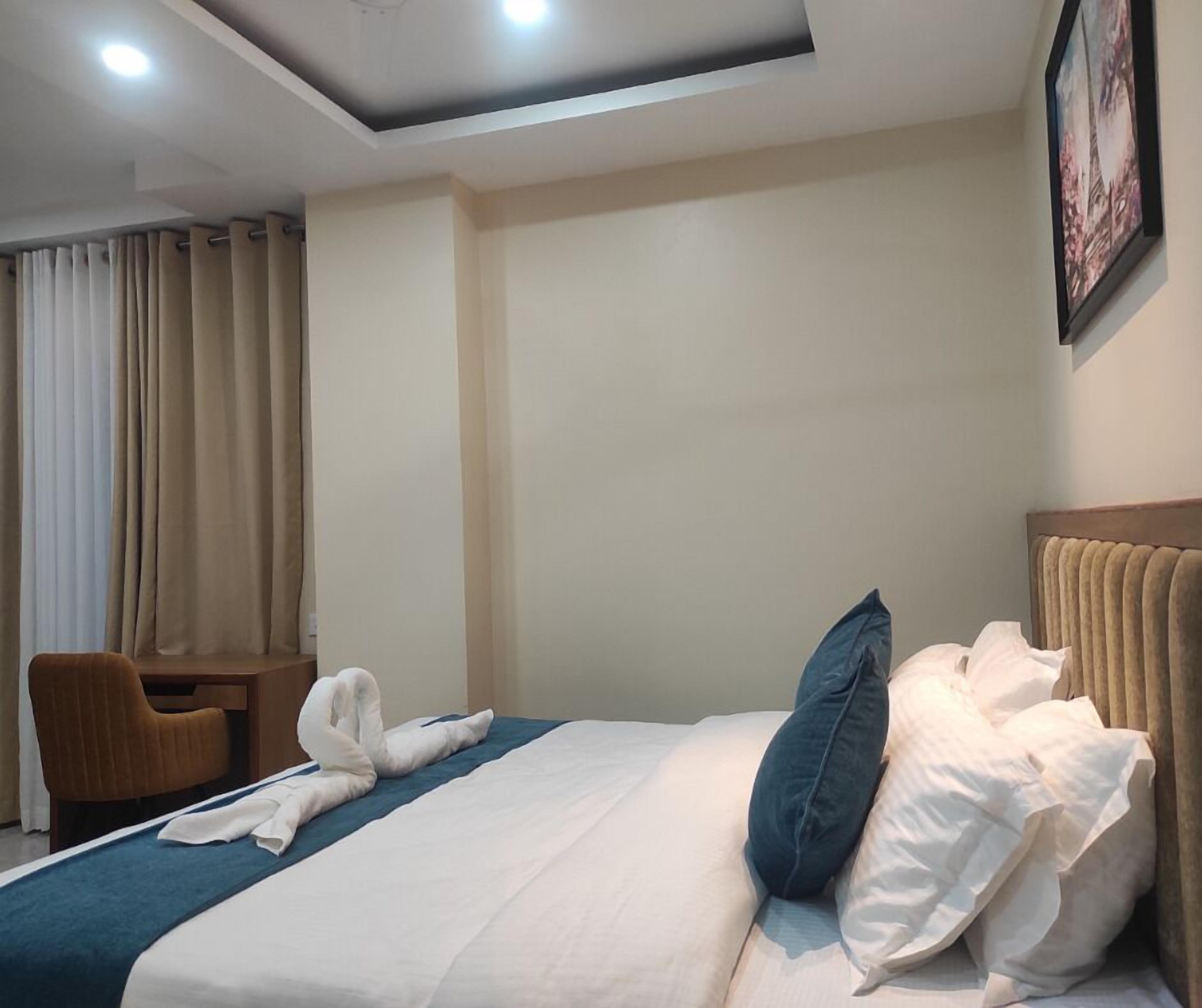 Habitación de hotel con cama, una silla, un escritorio y un cuadro en la pared.