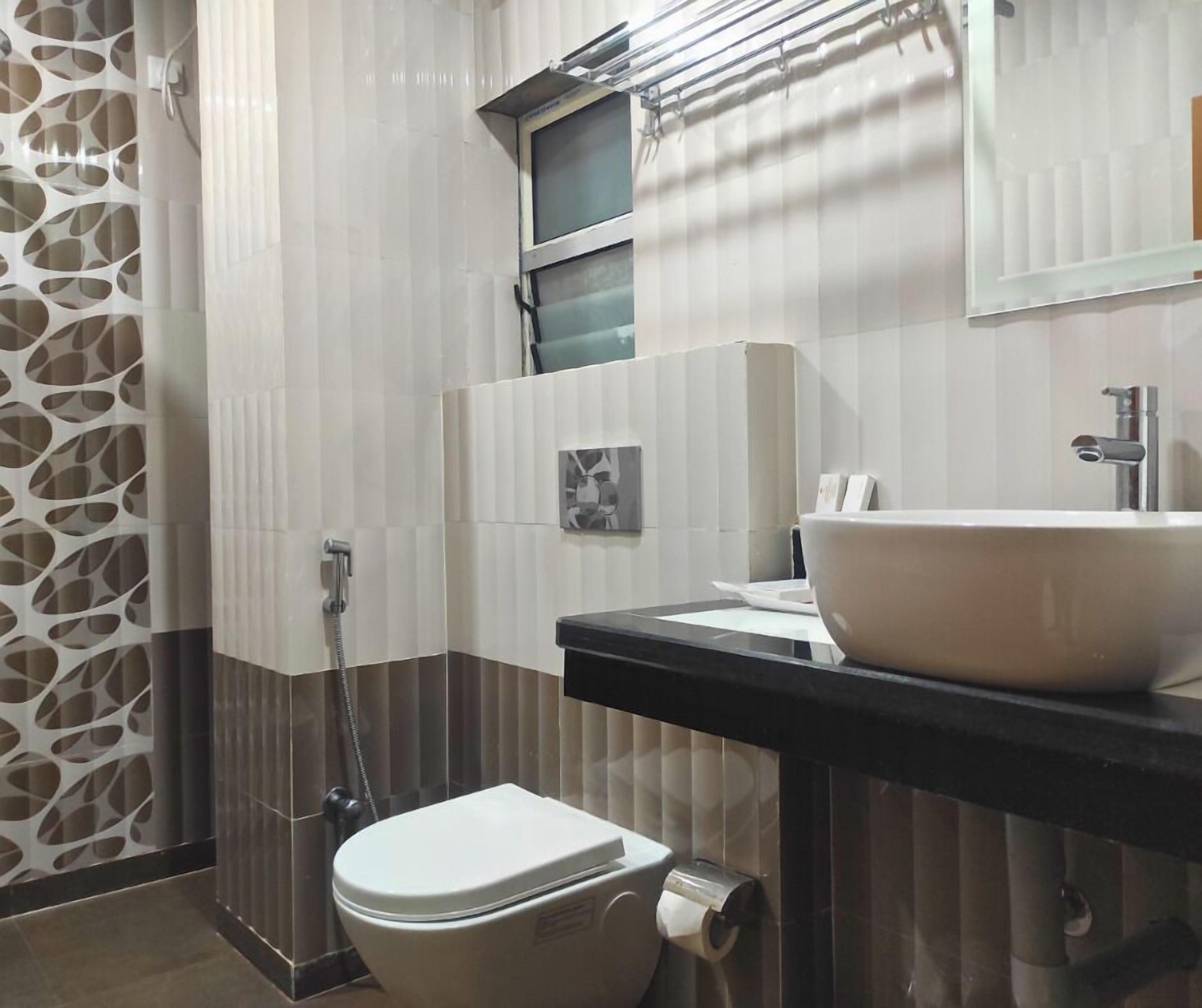 Uma casa de banho com sanita, lavatório e chuveiro.