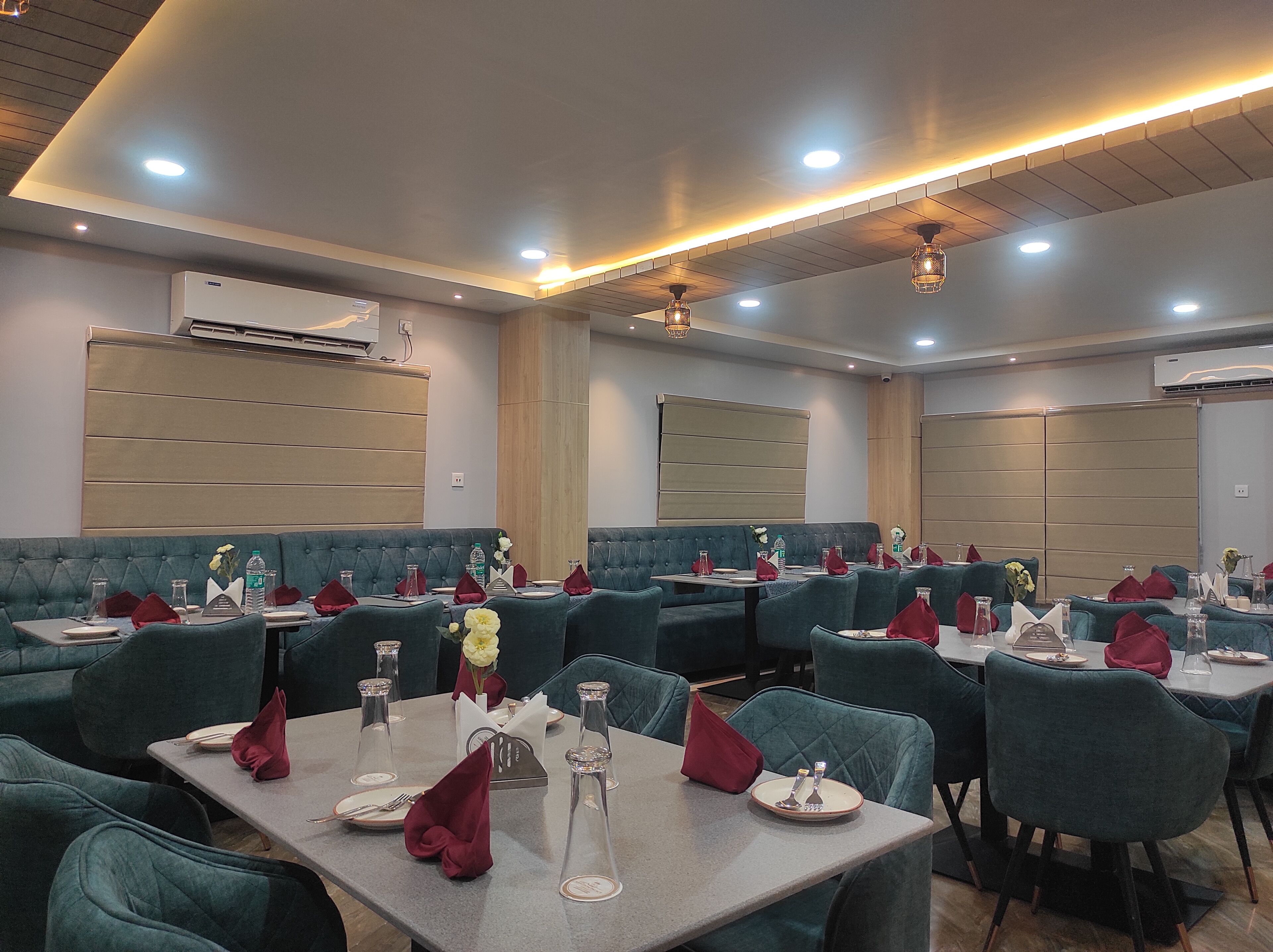 A restaurant with multiple tables and booths, each set with red napkins, clear glassware, and white plates.