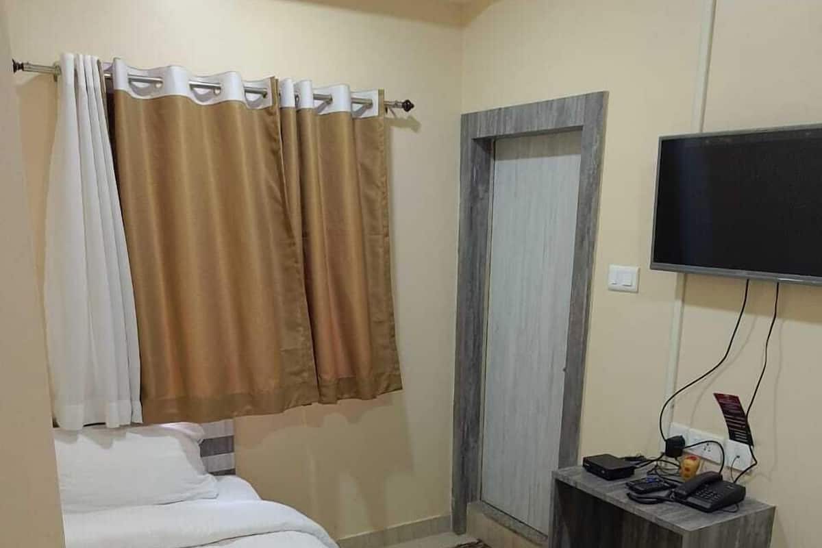 A hotel room with a bed, a desk with a TV, and a wardrobe.