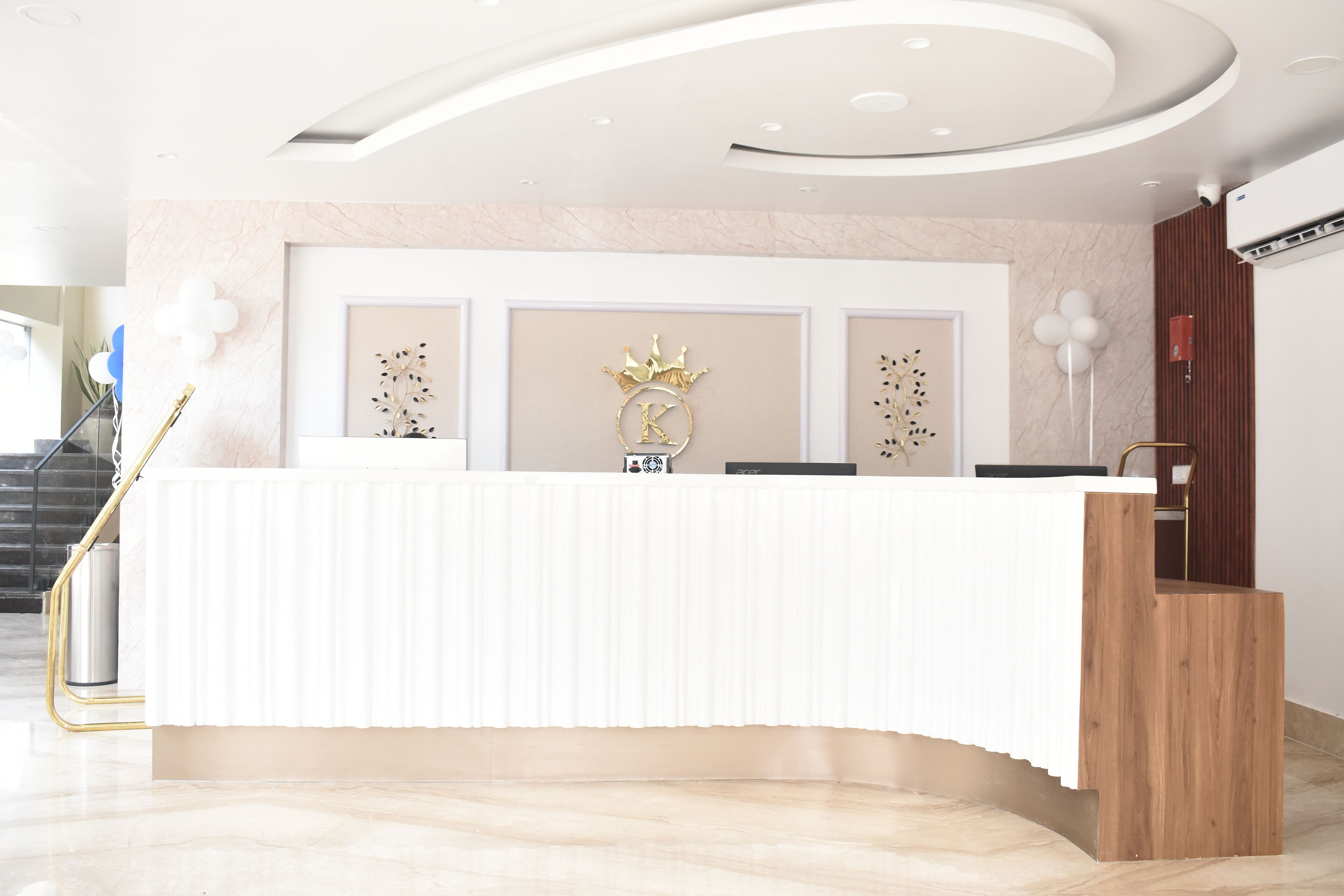 Un comptoir d’accueil doté d’un plan de travail blanc, d’un logo en forme de couronne et d’un élément décoratif en bois.