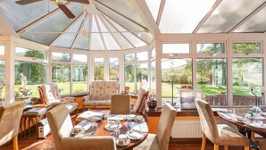 A conservatory with a dining table set for four, surrounded by comfortable seating. - Killean Farmhouse (Inveraray)