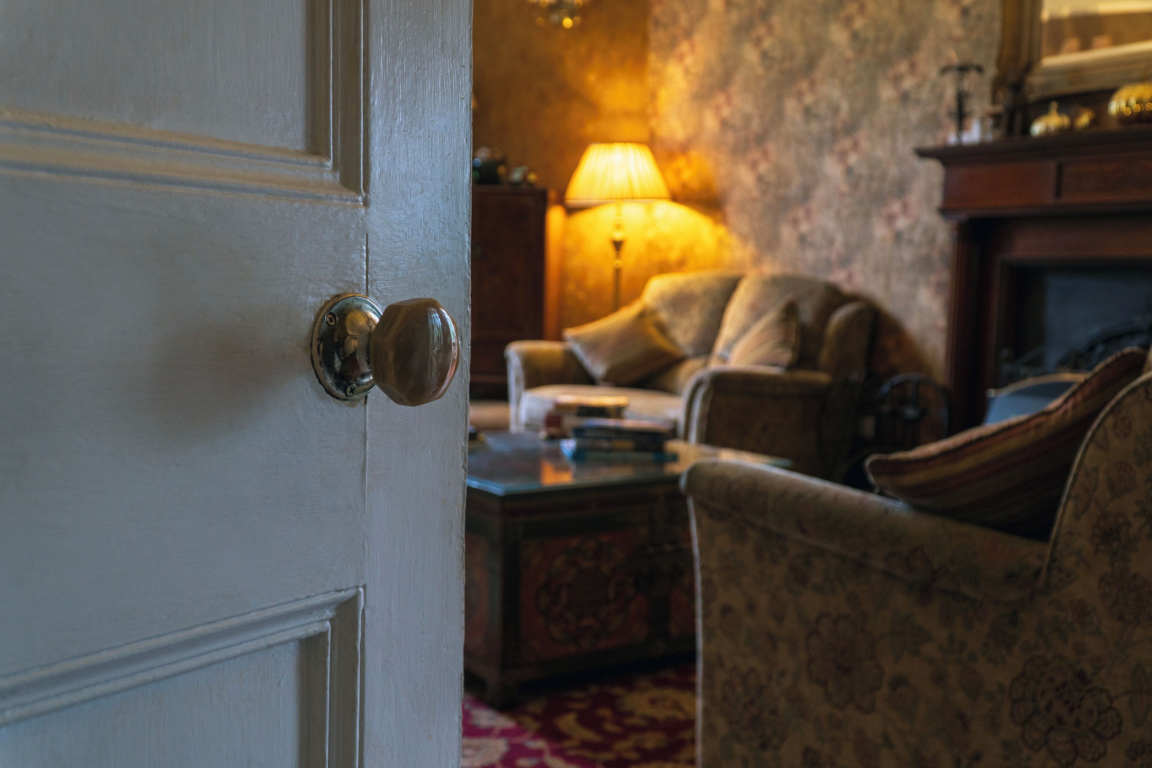 Una habitación con una puerta blanca, una lámpara, un sofá y un tapete estampado.