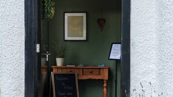 A doorway with a chalkboard sign, wooden furniture, and potted plants.