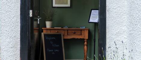A doorway with a chalkboard sign, wooden furniture, and potted plants.