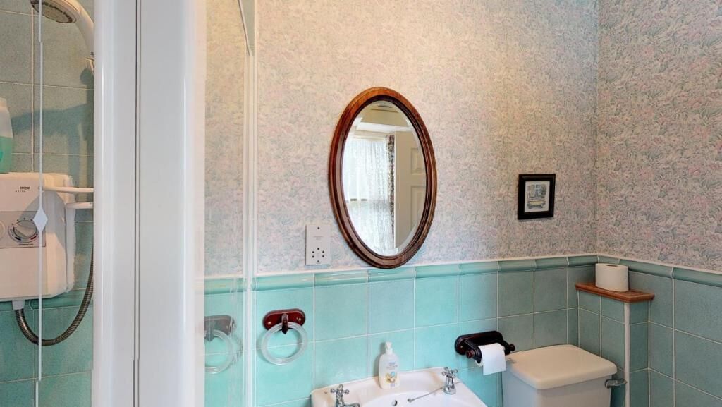Un baño con ducha, inodoro, lavabo y espejo.