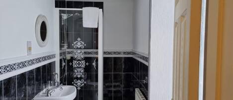 A bathroom with a sink, mirror, and shower.