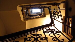A staircase with ornate black metal railings and a small window at the top.