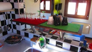 A kitchen with a checkered backsplash, a red countertop, and various kitchen items.