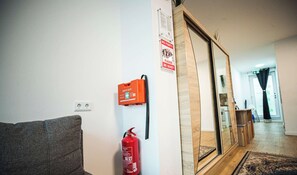 A hallway with a fire extinguisher, a 'NO PARTY' sign, and a 'PLEASE BE QUIET' sign.