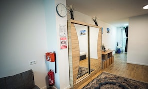 Ein modernes Interieur mit Holzboden, einer Couch, einem kleinen Tisch mit einer Flasche und einem Spiegel.