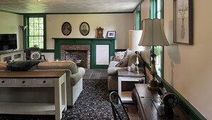 Ein gemütliches Wohnzimmer mit Kamin, grünen Wänden und einem gemusterten Teppich.
