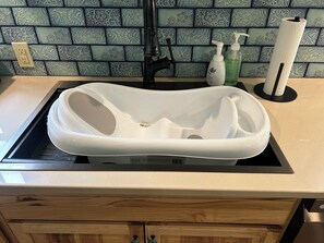 Un lavabo blanc posé sur un plan de travail noir, avec un pare-éclaboussures carrelé.