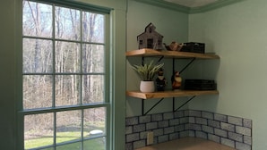 Eine Küche mit großem Fenster, Holzregalen, einem Blumentopf und Fliesen mit Muster.