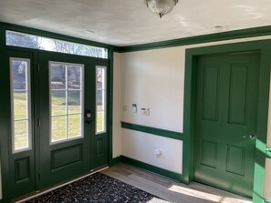 A hallway with green doors, a patterned rug, and a ceiling light fixture.