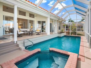 A swimming pool with a glass ceiling, a sun lounger, and a patio area with outdoor furniture. - 3BR, 2BA waterfront home near Marco Island Beach with heated pool. (Marco Island)