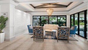 A modern lobby with a sofa, two armchairs, a coffee table, and a chandelier. - Beachfront 1BR condo on Marco Island with pool, WiFi, and kitchen (Marco Island)