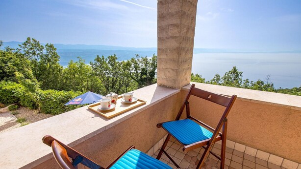 A balcony with two wooden chairs and a tray with cups and a teapot. - Stunning home in Veprinac with sauna (Veprinac)