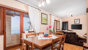 A dining area with a table and chairs, a sofa, and a TV in the living room. - Stunning home in Veprinac with sauna (Veprinac)