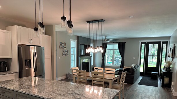 A modern kitchen with a large island, stainless steel appliances, and pendant lighting. - Hidden Hollow - Your Outdoor destination (Greig)