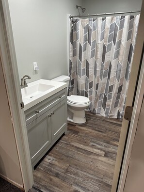 Une salle de bain avec un lavabo blanc, des toilettes et un rideau de douche à motifs géométriques.