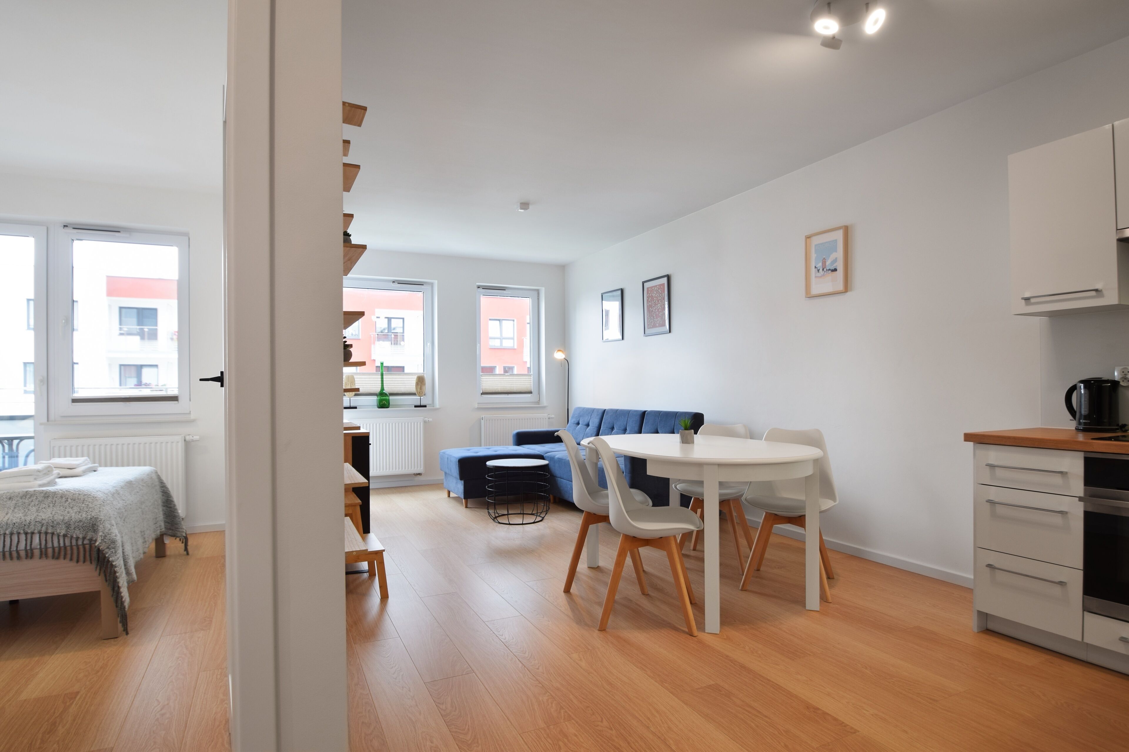 Un apartamento moderno con comedor, cocina y sala de estar, que incluye un sofá y una pequeña mesa.
