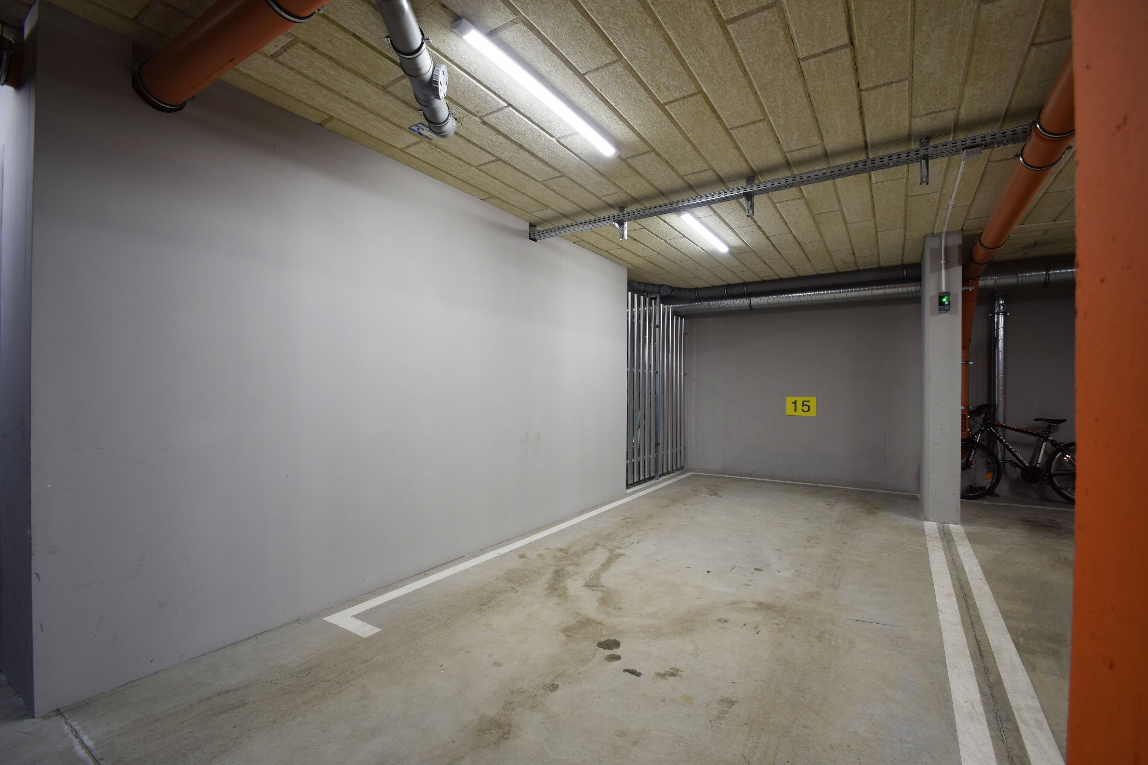 Eine saubere, leere Tiefgarage mit Betonböden, Metallgeländern und Neonbeleuchtung.