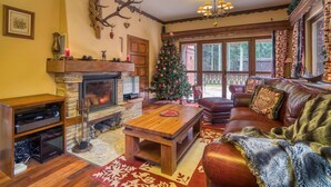 Una sala de estar acogedora con chimenea, un árbol de Navidad, un sofá de cuero y una mesa de centro de madera.