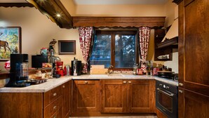 Una cocina con armarios de madera, estufa y ventana con cortinas.