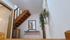 A wooden staircase leading to a landing with a mirror and a small shelf with decorative items.
