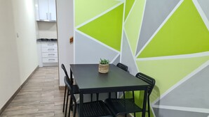 A dining area with a table and chairs, a potted plant, and a geometric-patterned wall.