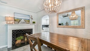 A dining area with a wooden table, chairs, a fireplace, and a chandelier.