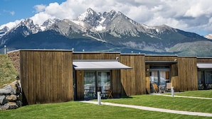Un edificio moderno con paredes exteriores de madera, amplias puertas correderas de vidrio y mobiliario exterior.