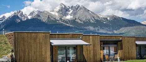 Un edificio moderno con paredes exteriores de madera, amplias puertas correderas de vidrio y mobiliario exterior.
