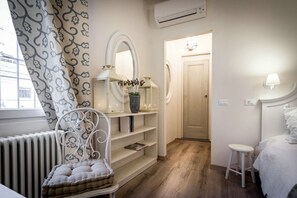 A bedroom with a radiator, a chair, a bedside table, a bed, a mirror, and a door leading to another room. - Como unique View - My Home in Como (Como)