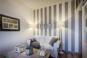 Une pièce avec un mur à rayures, un canapé blanc, deux lampadaires et une table ornée de lanternes décoratives.