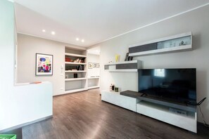 Een moderne woonkamer met een flatscreen televisie, inbouwkasten en een houten vloer.