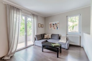 A modern living room with a grey sofa, a coffee table, and a radiator. - Shimmering Waters - My Home In Como (MOLTRASIO)