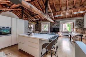 A spacious kitchen with a large island, stone walls, and wooden beams. - La Corte delle Rondini - My Home in Como (Como)