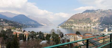 A panoramic view of a lakeside town with buildings, mountains, and a clear sky.