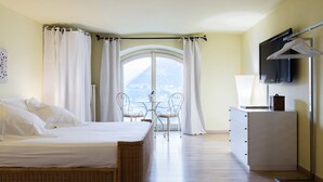 A bedroom with a bed, a desk, a TV, and a view of the outdoors.