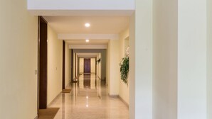 A long, well-lit hallway with a polished floor, leading to multiple doors.